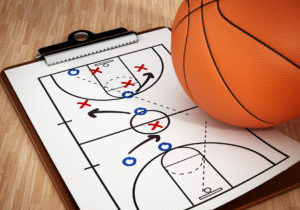 Basketball and strategy board standing on wooden surface.